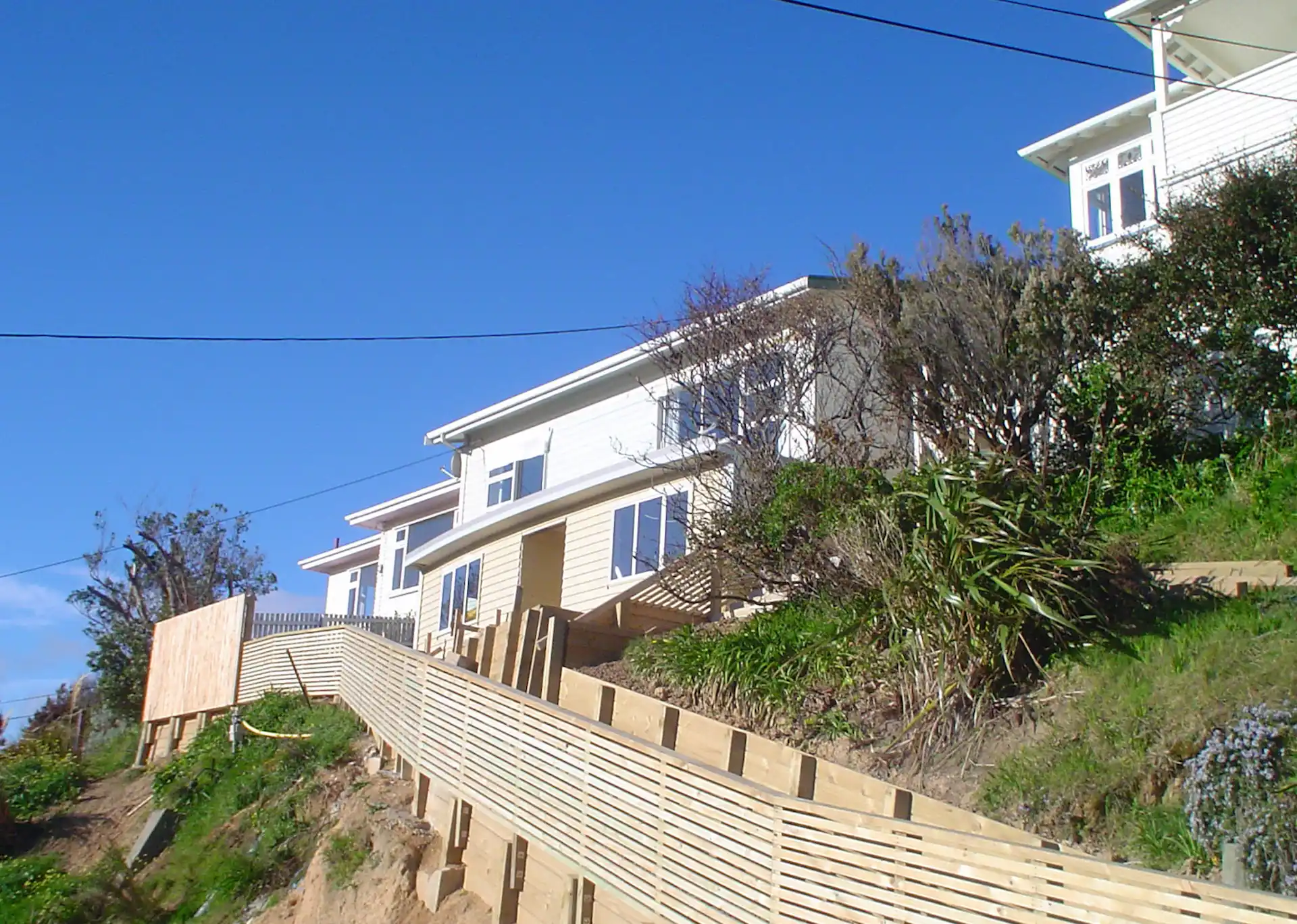 Hillside home in Porirua with timber retaining wall and walkway